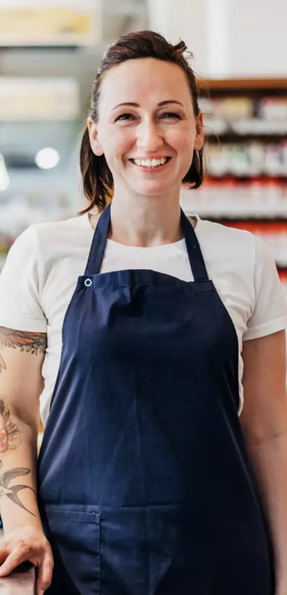 Une jeune femme en tablier sourit